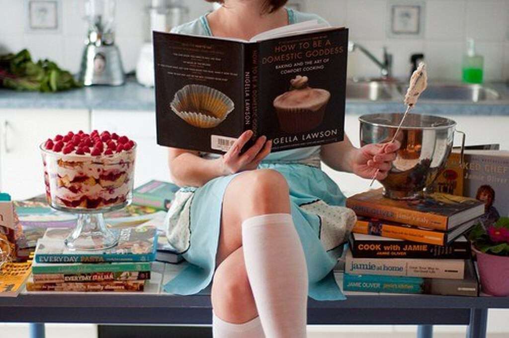 Книга дела домашние. Фотосессия на кухне готовка. Девушка с книжкой и едой. Кулинария книга. Девушка с книгой на кухне.