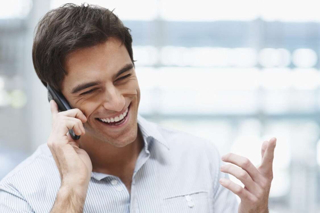 Laughing young guy enjoying a conversation over the cellphone