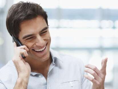 Laughing young guy enjoying a conversation over the cellphone