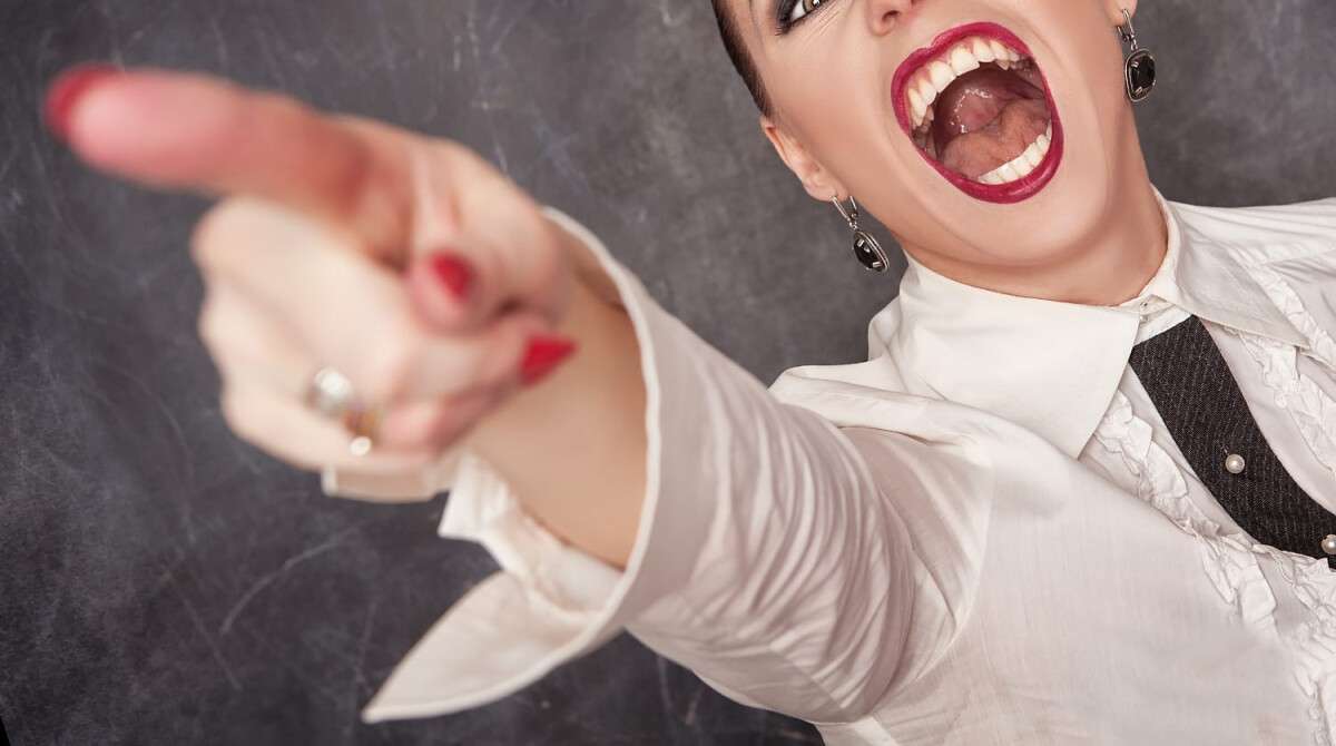 Angry screaming woman in white blouse pointing out
