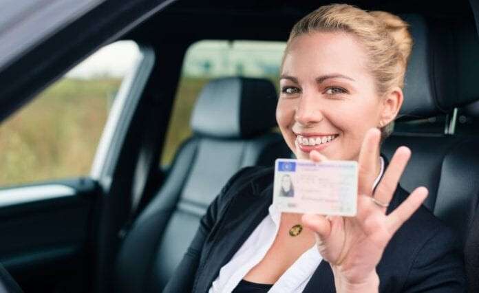 Woman showing her driving license out of car window