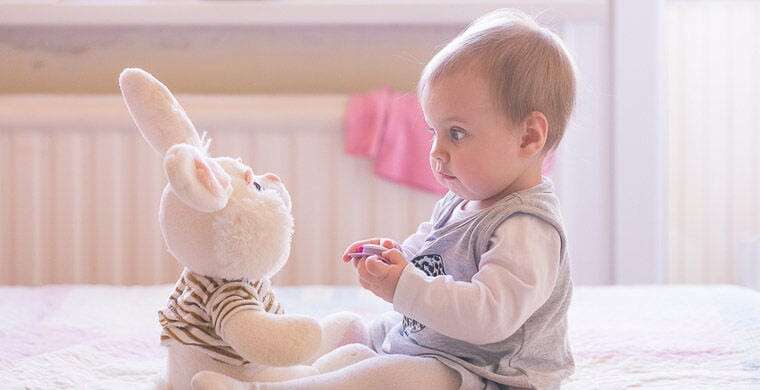 Baby girl playing with plush rabbit