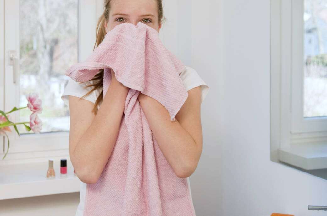 Teenage girl wiping her face with towel