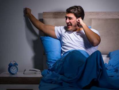Young man struggling from noise in bed