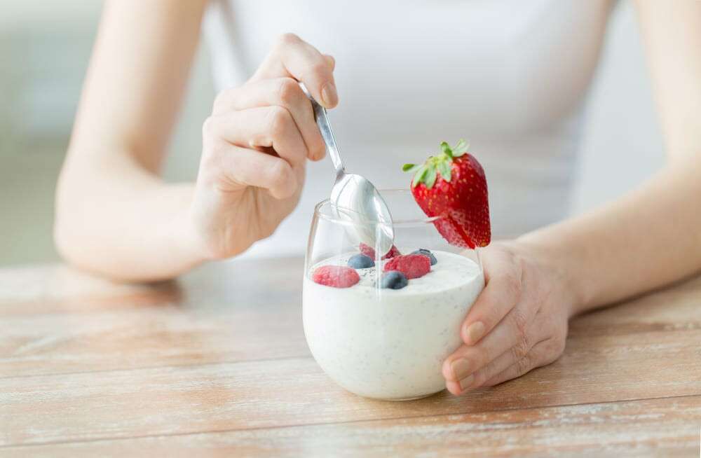 close up of woman hands with yogurt and berries