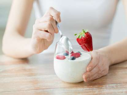 close up of woman hands with yogurt and berries
