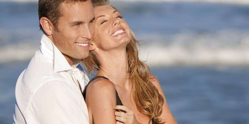 Man and Woman Couple Laughing In Romantic Embrace On Beach