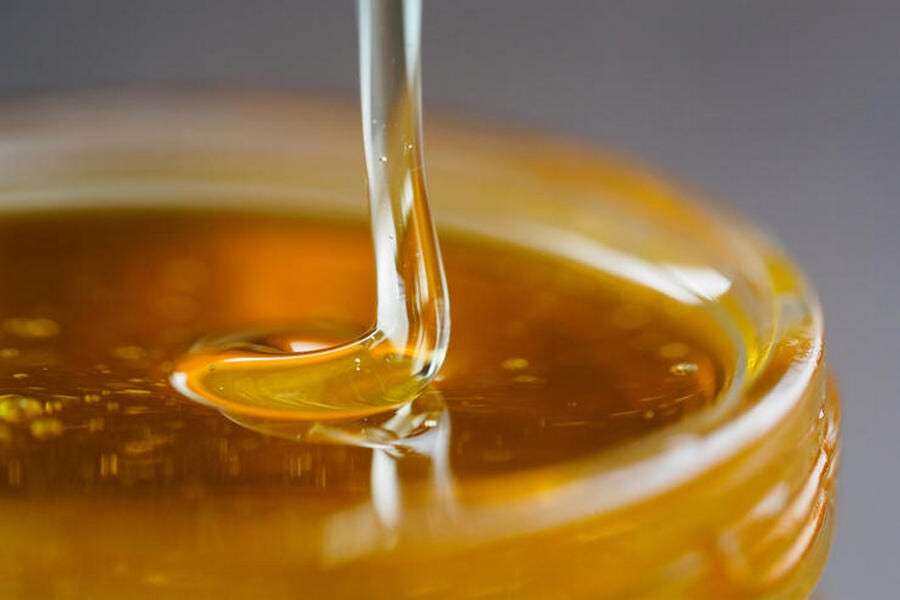 Honey falling in jar extreme close up