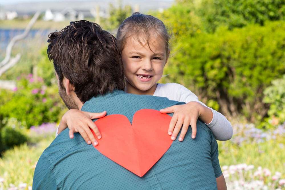 Daughter giving dad a heart card in the countryside