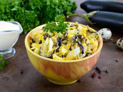 Spicy salad of fried eggplant, boiled egg, marinated onions in a bowl.