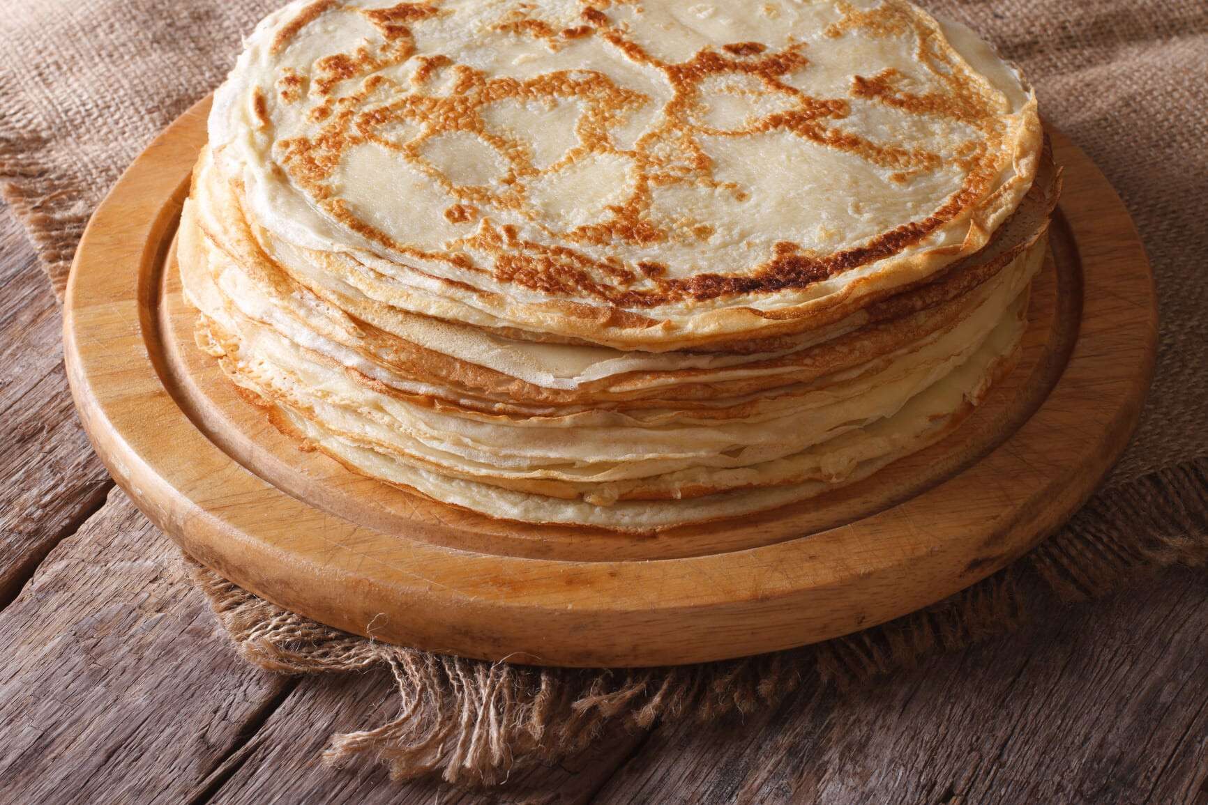 pile of crepes on a kitchen board on the table. horizontal