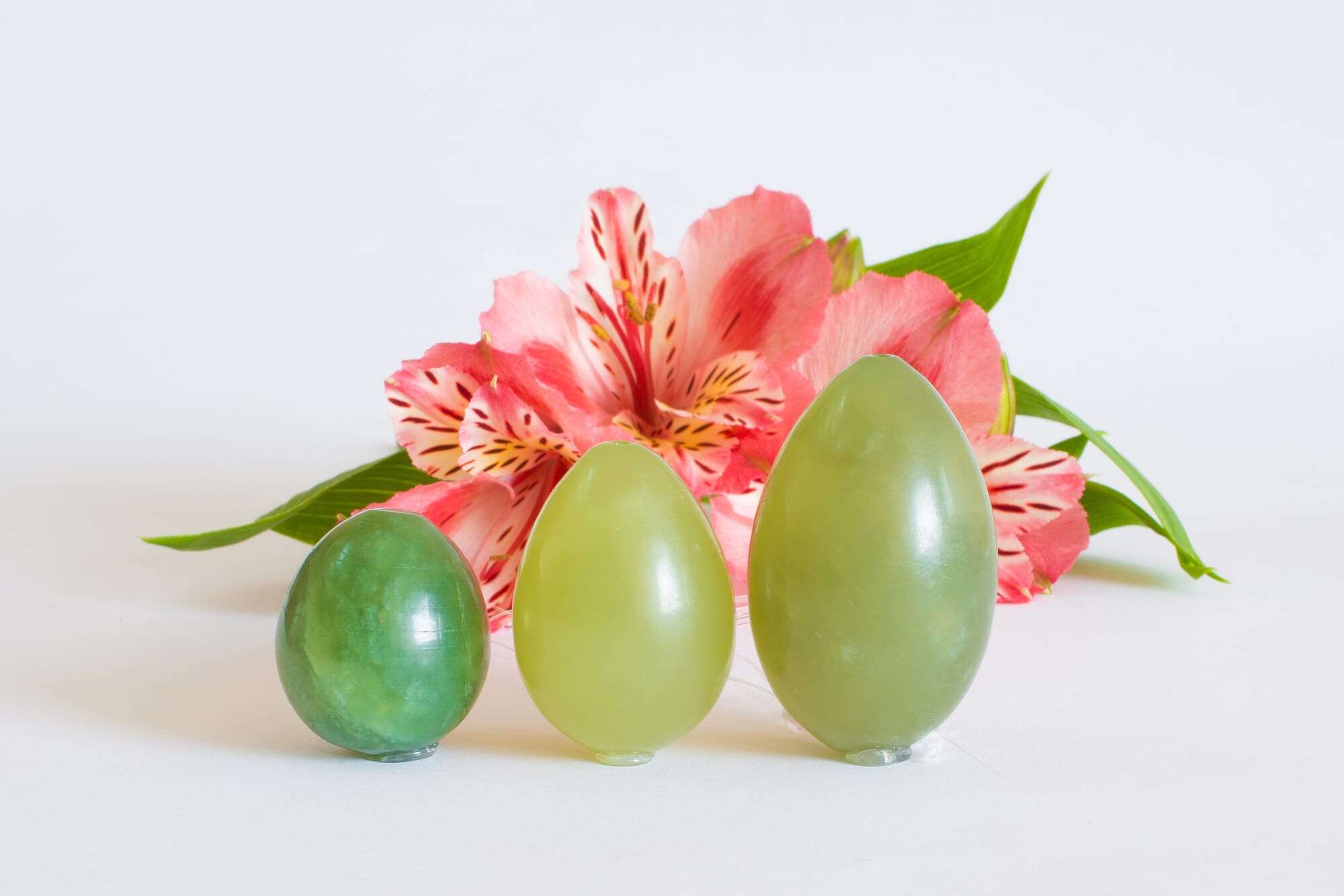 Jade eggs stand near a pink flower