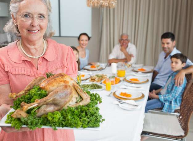 grandmother-holding-chicken-roast-with-family-at-dining-table_13339-71889